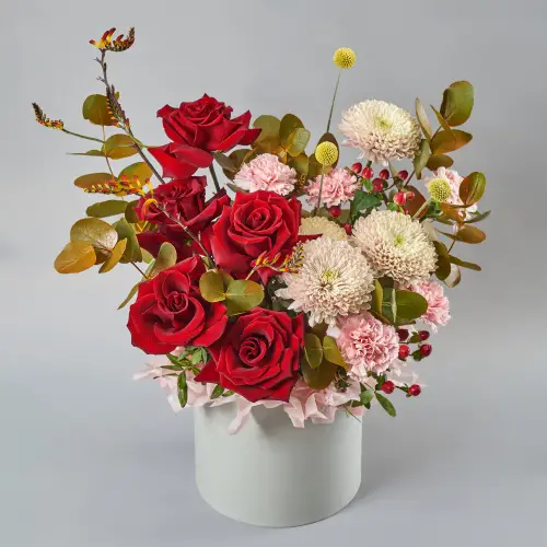 Цветочная композиция из роз, хризантем и гиперикума с краспедией в шляпной коробке